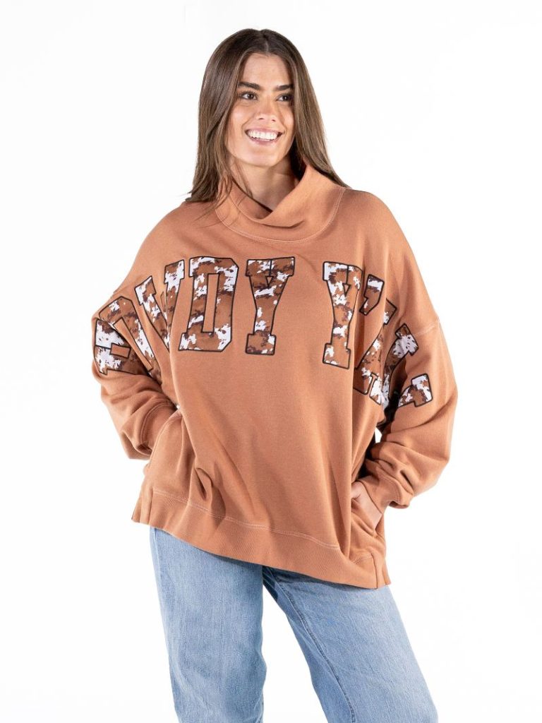The Everyday Mock Neck Sweatshirt features bold front graphics in Howdy Y'all text in cow print , ribbed cuffs and a mock neck.