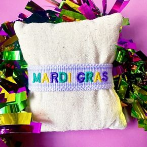 Get parade-ready with this adorable Mardi Gras bracelet featuring classic purple, green, and gold letters on a soft lavender woven band! 