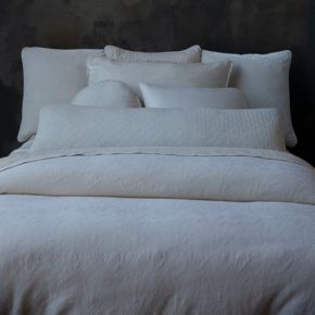 A straight on shot of a monochromatic bed dressed in neutral tones