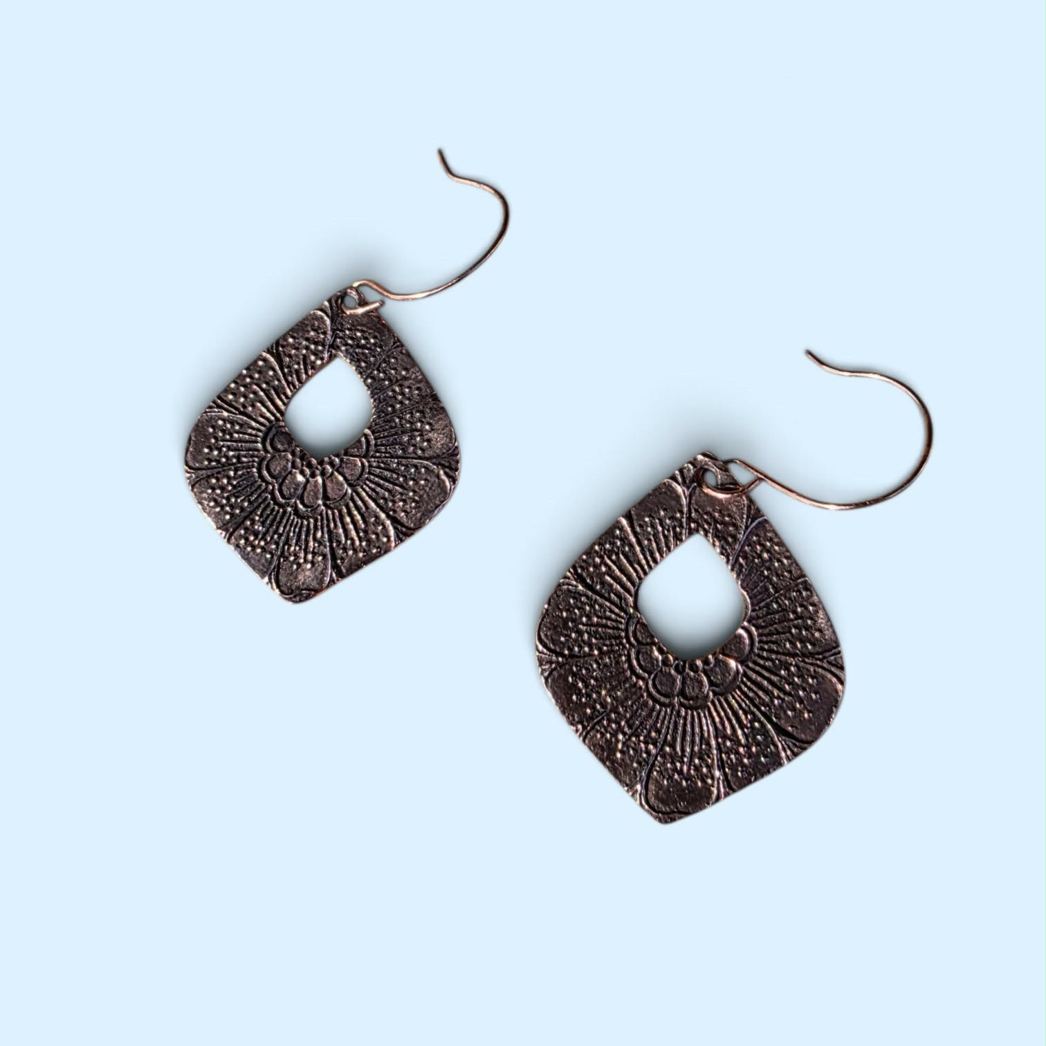 Handcrafted bronze drop earrings featuring an intricate botanical texture, geometric silhouette, and rich darkened patina. Lightweight, dimensional, with an artful edge for everyday wear.