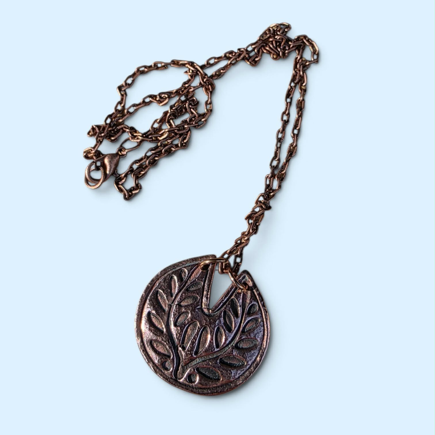 Handcrafted bronze pendant necklace featuring an intricate leafy botanical design and rich darkened patina. Organic, earthy, and timeless, with the feel of a tiny heirloom unearthed from nature.