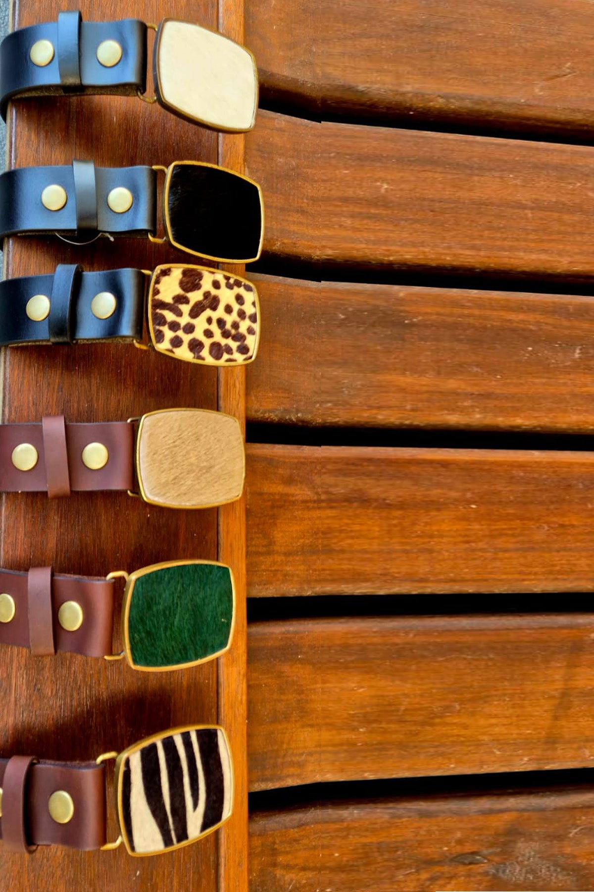 Handcrafted in South Africa, genuine leather belts pair with interchangeable hair-on-hide buckles in distinctive colors and patterns for a unique equestrian accessory.