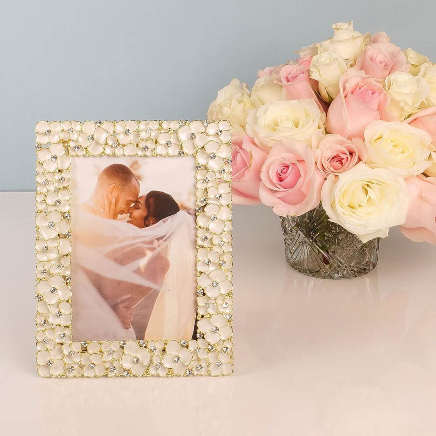 Delicate dogwood blossoms richly cast into a gold finished pewter picture frame, with intricate ivory hued hand-enameling and hand-set clear European crystals.