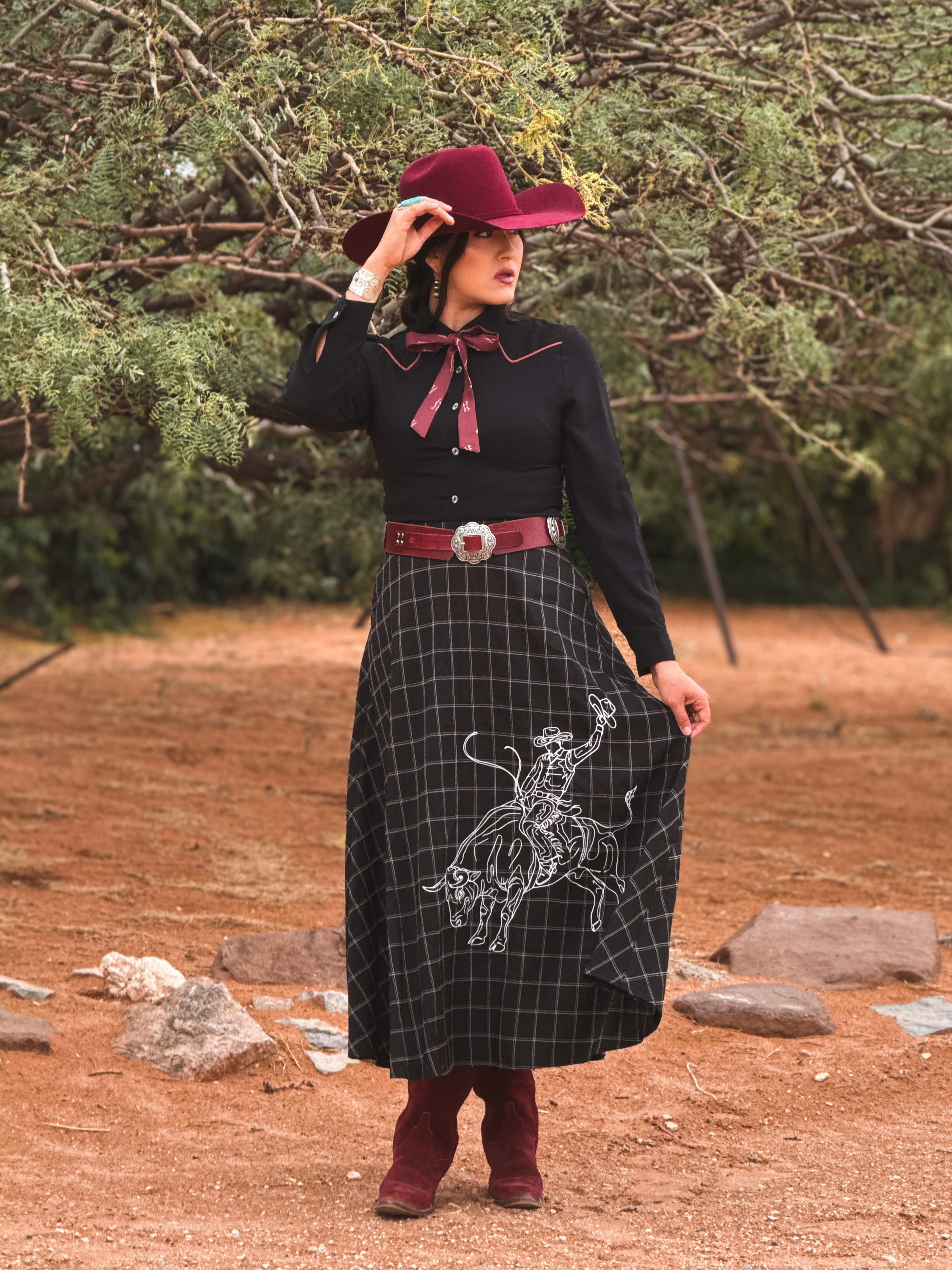 Western Rodeo Embroidered Maxi Skirt Outfit: black plaid maxi skirt with white cowboy embroidery, burgundy hat, belt, boots, and black top for rodeo, concerts, or Western boutique styling.